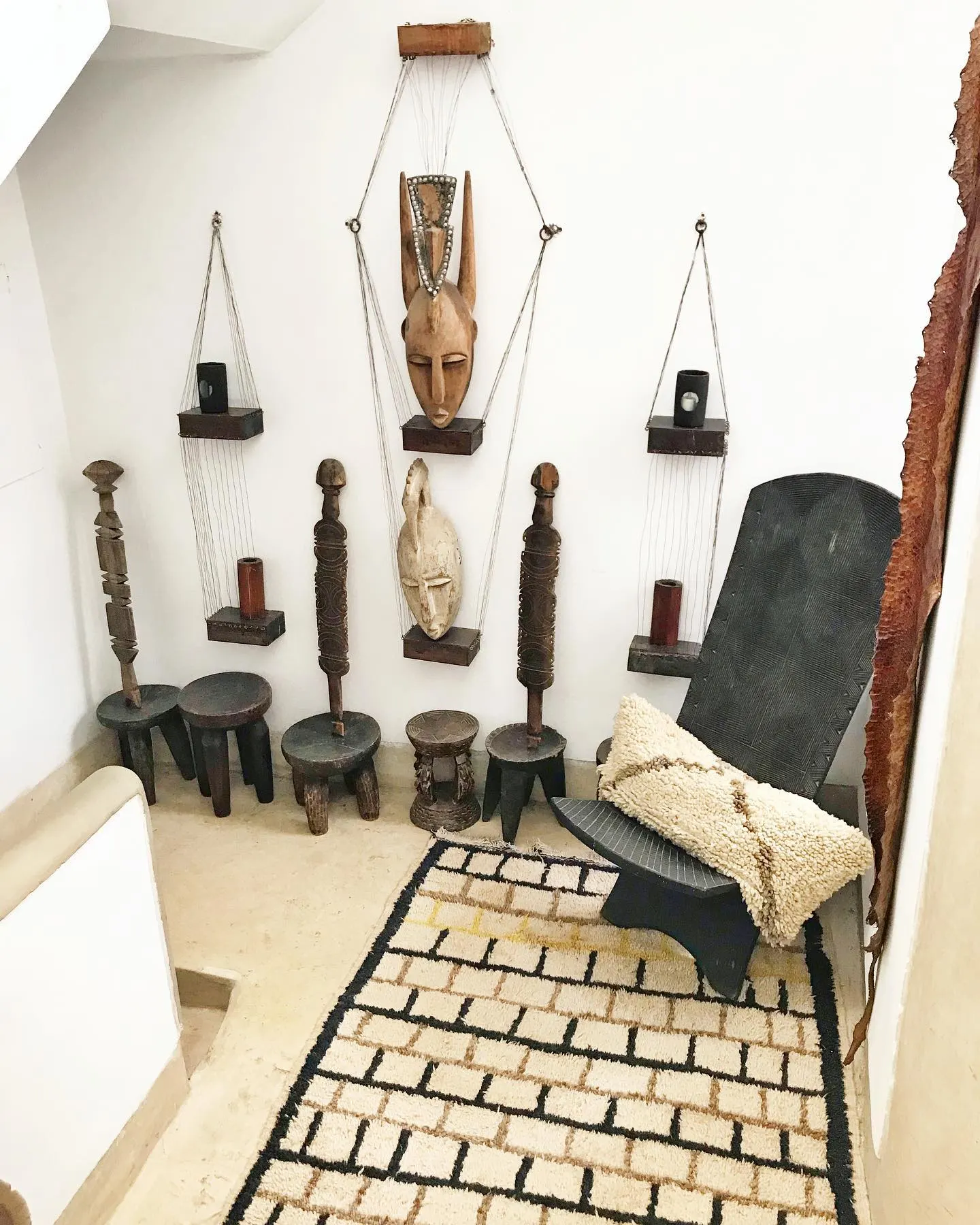 A collection of carved artifacts and lamps against a white wall