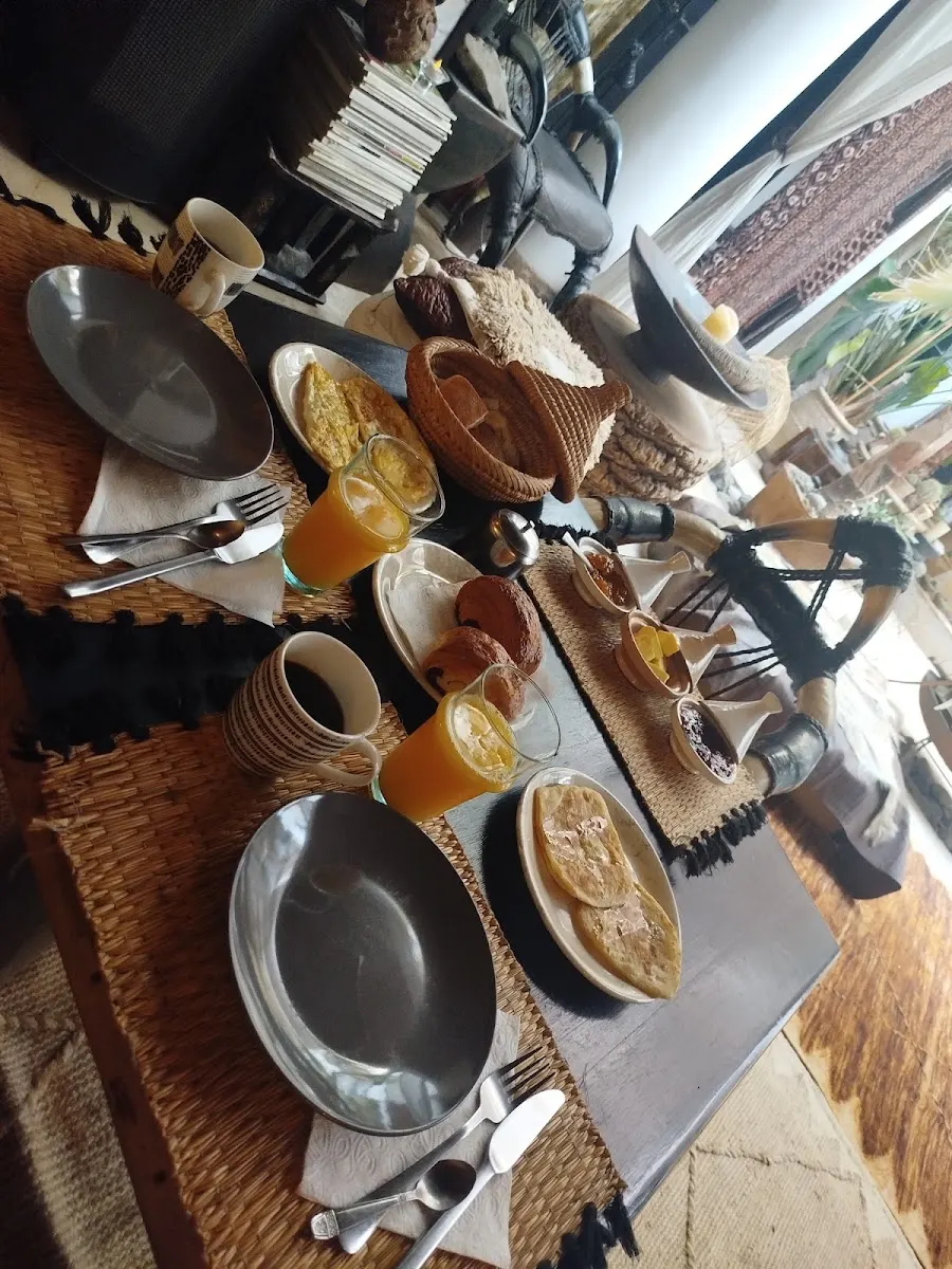 Breakfast laid out on a woven table: coffee, fresh orange juice, warm breads and msemen