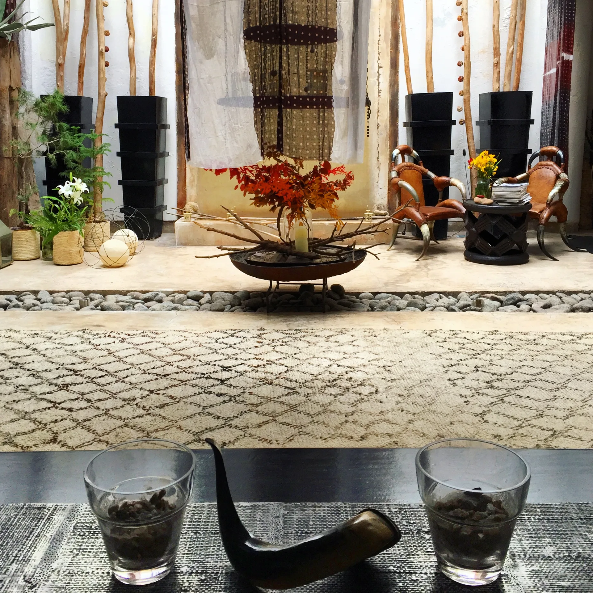 A styled corner of the house: Beni Ourain rug, horn chairs, a branch centrepiece on stone