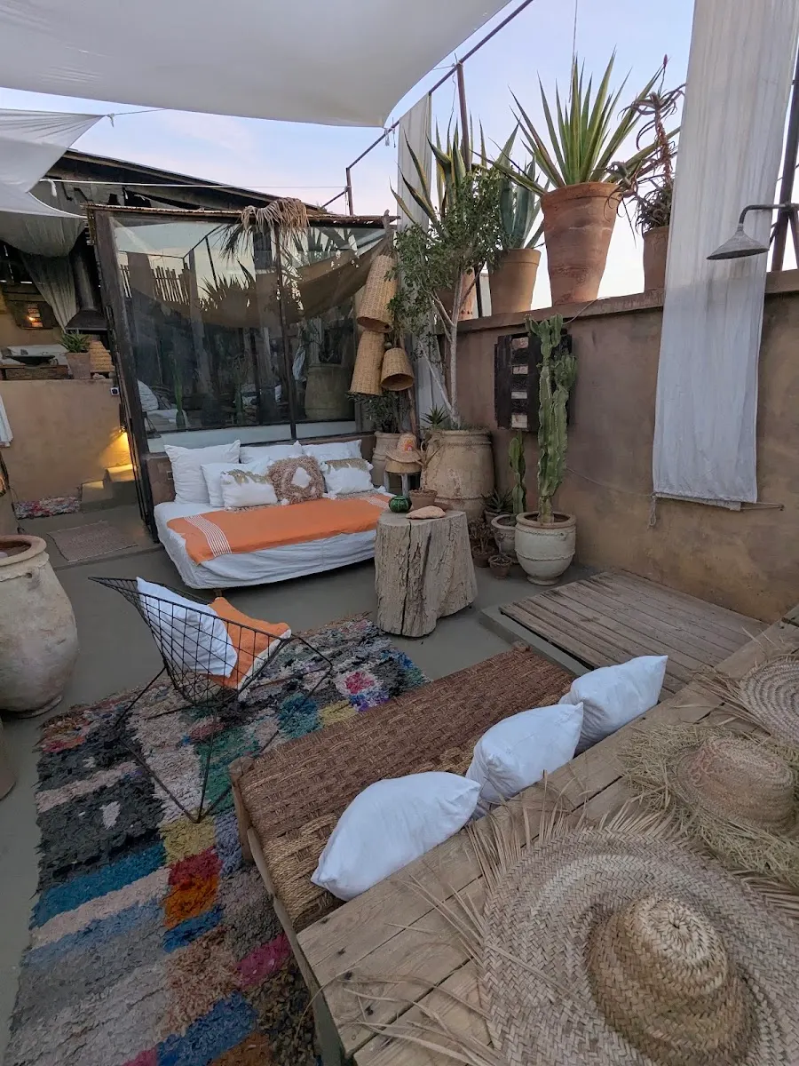 Dusk on the roof: white cushions, boucherouite rugs and the sky fading over the terraces