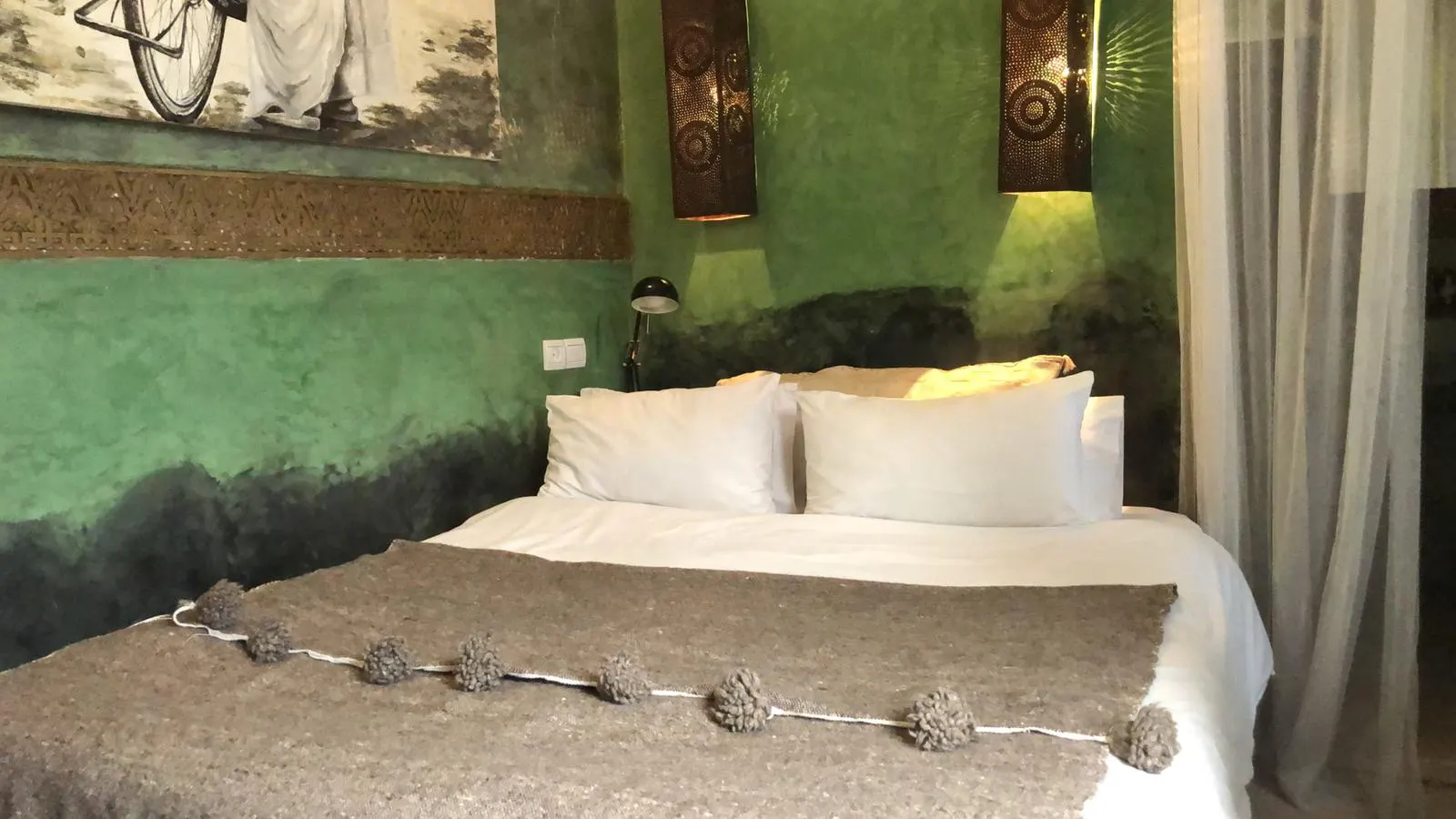 The green room: moss-green tadelakt walls, pierced-copper sconces, white bedding