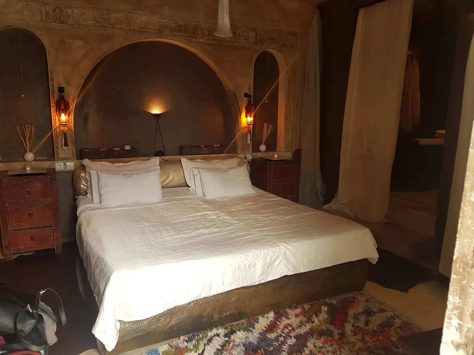 A bed set beneath a warm tadelakt arch, lantern light on the walls