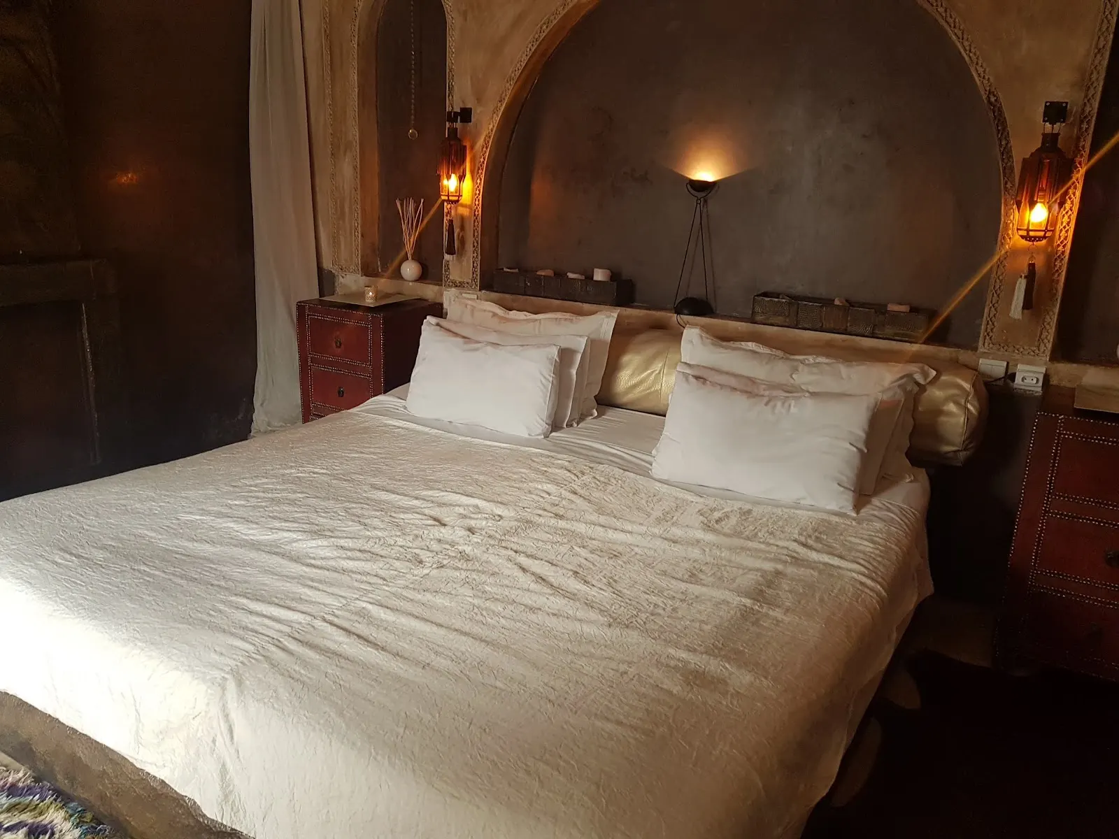A bed under lantern light, wool pompom throw