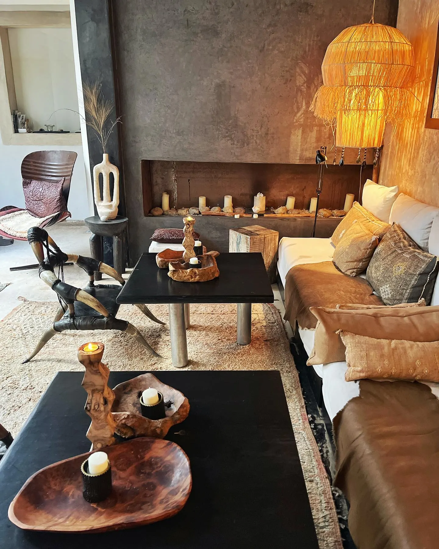 The candle-lit salon of Riad Lola: raffia pendant, earthen walls, linen sofas